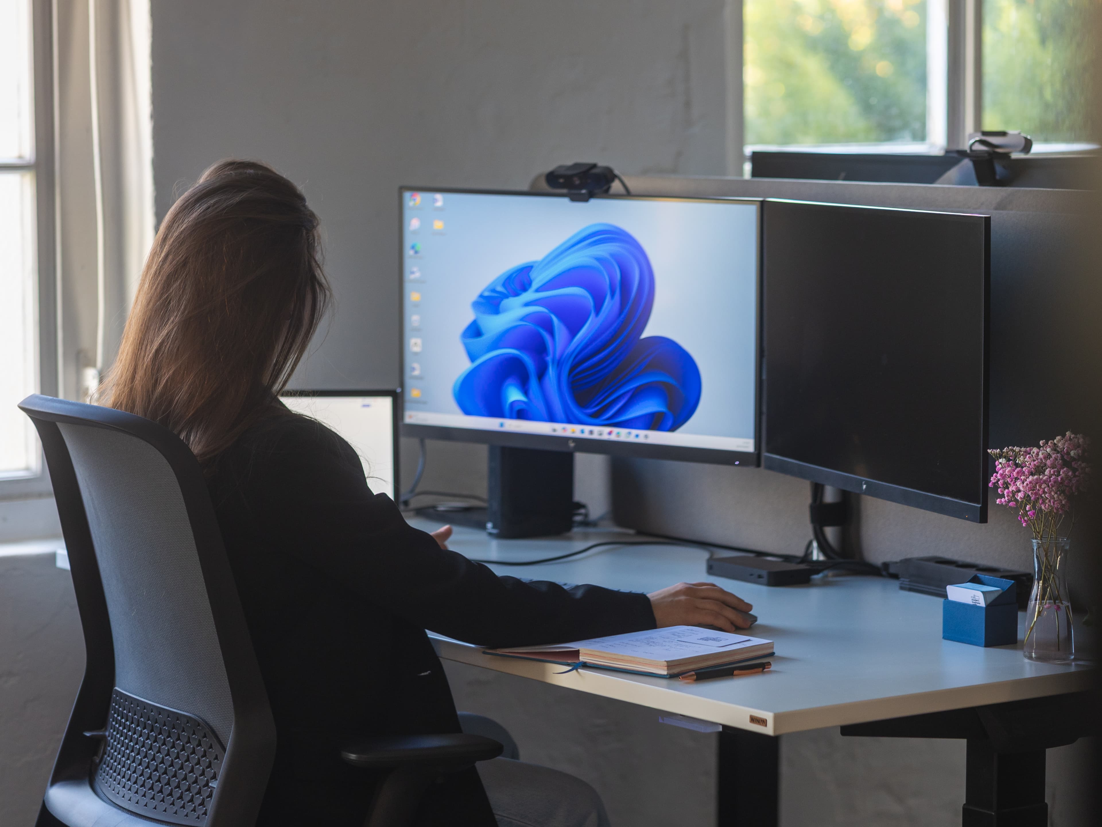 Person an einem Arbeitsplatz mit zwei Monitoren